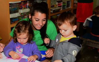counselor with two young children doing arts and crafts