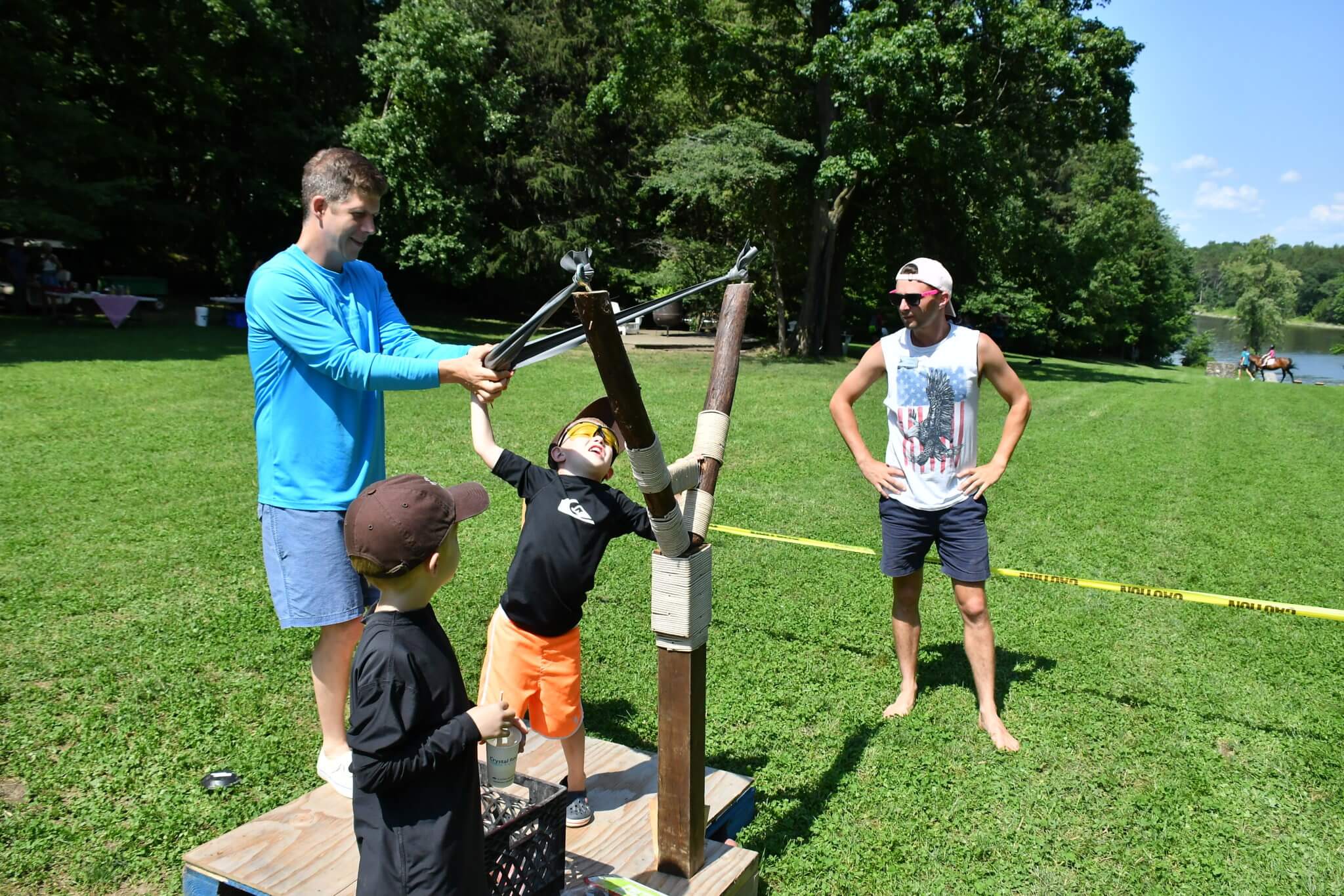 guests using giant sponge sling shot near the lake