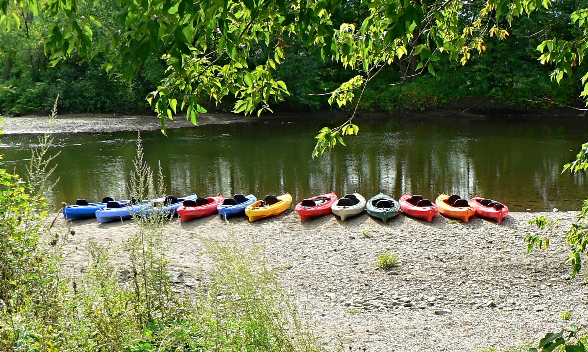 colorful kayaks lined up on the beach river