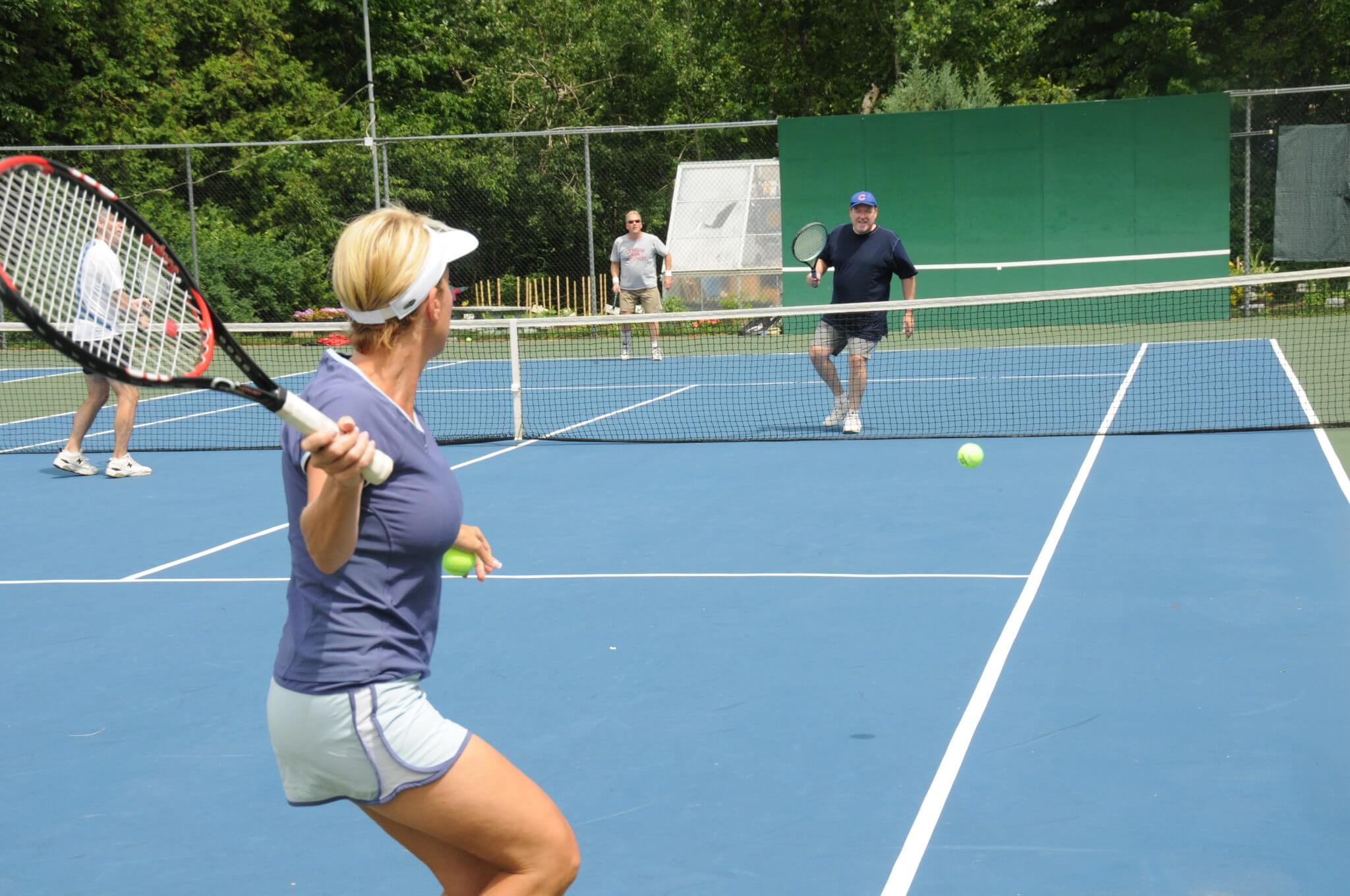 man and woman playing tennis on the inn court
