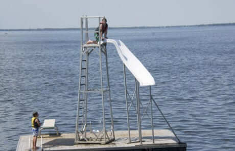 Waterslide on floating dock. Two guest children climbing ladder