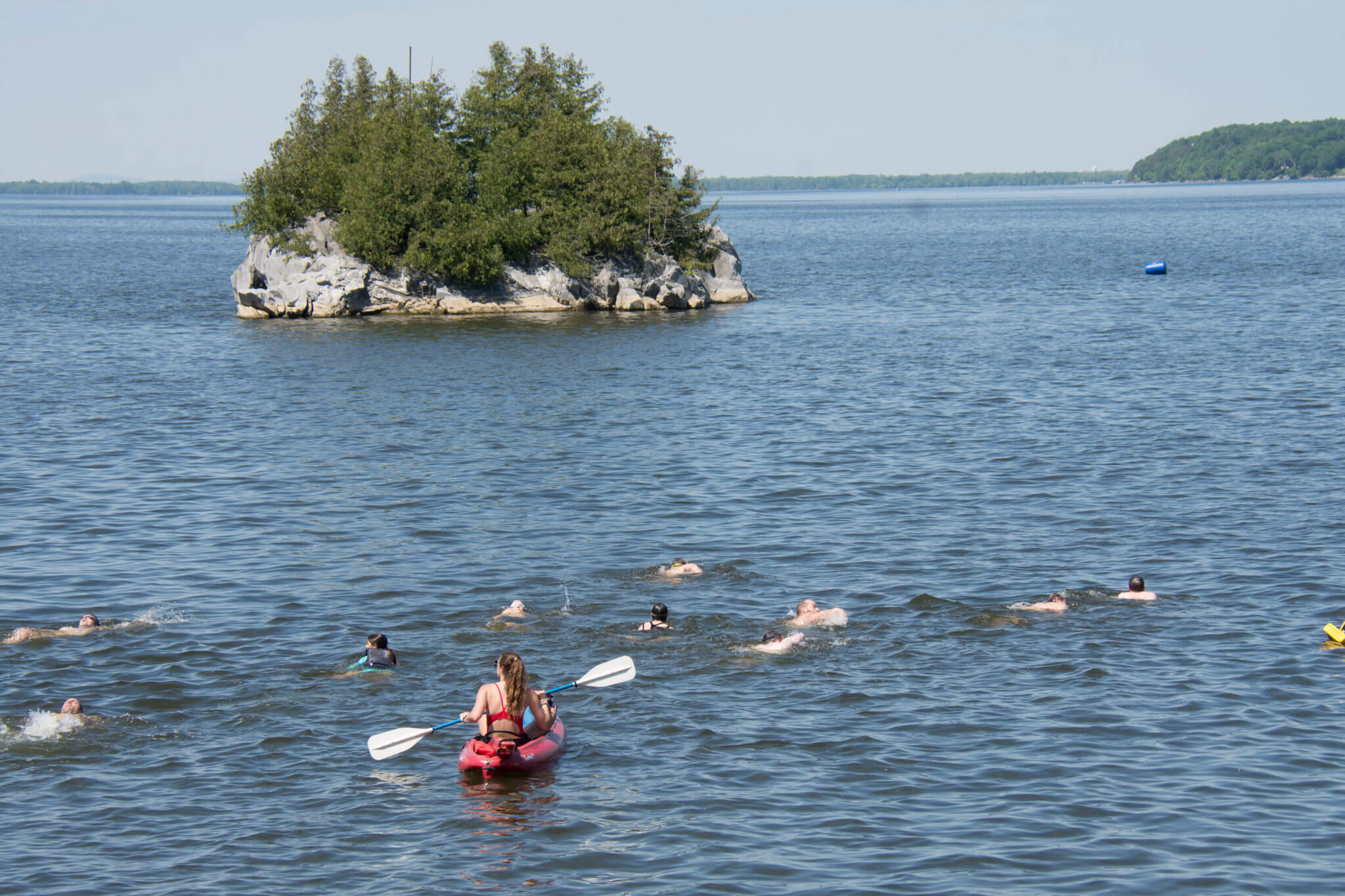 Guests swimming towards Bandstand Island accompanied by lifeguard kayaker